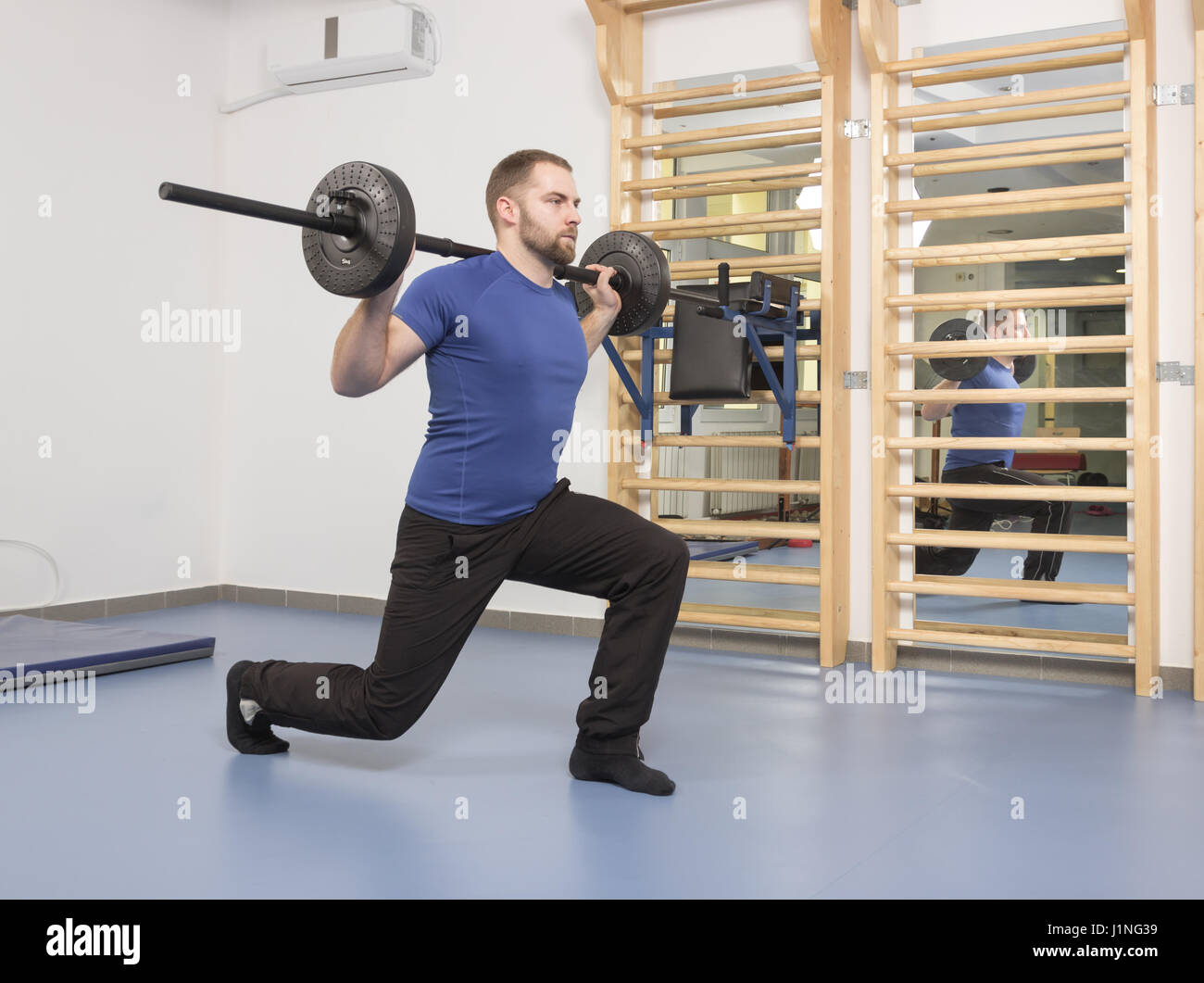 ein junger Mann nur, Gewicht Bar, Fitness-Übung im Innenbereich Stockfoto