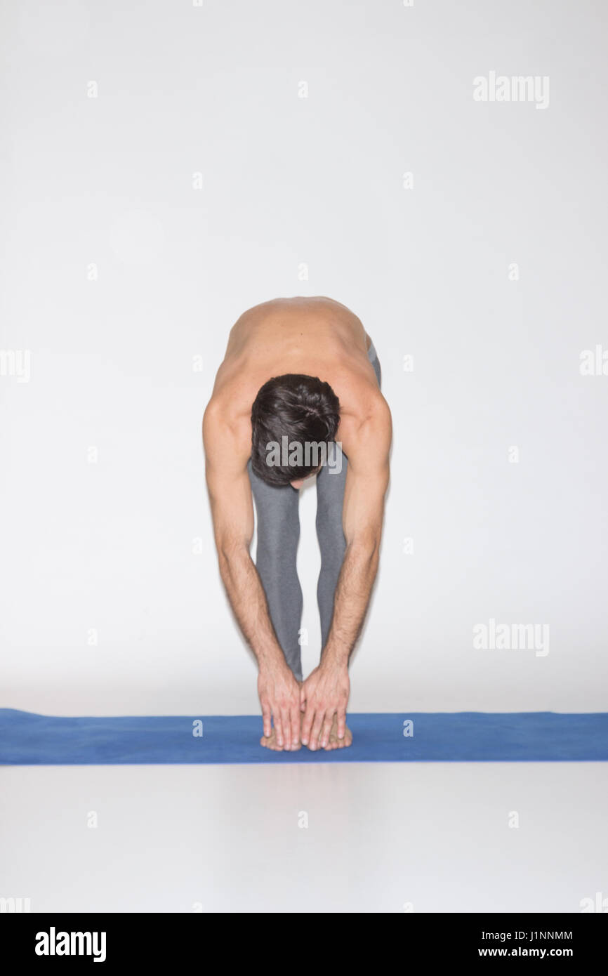 junger Mann, Dehnung, berühren die Zehen flexibel. Studio-weißem Hintergrund-Matte. Stockfoto