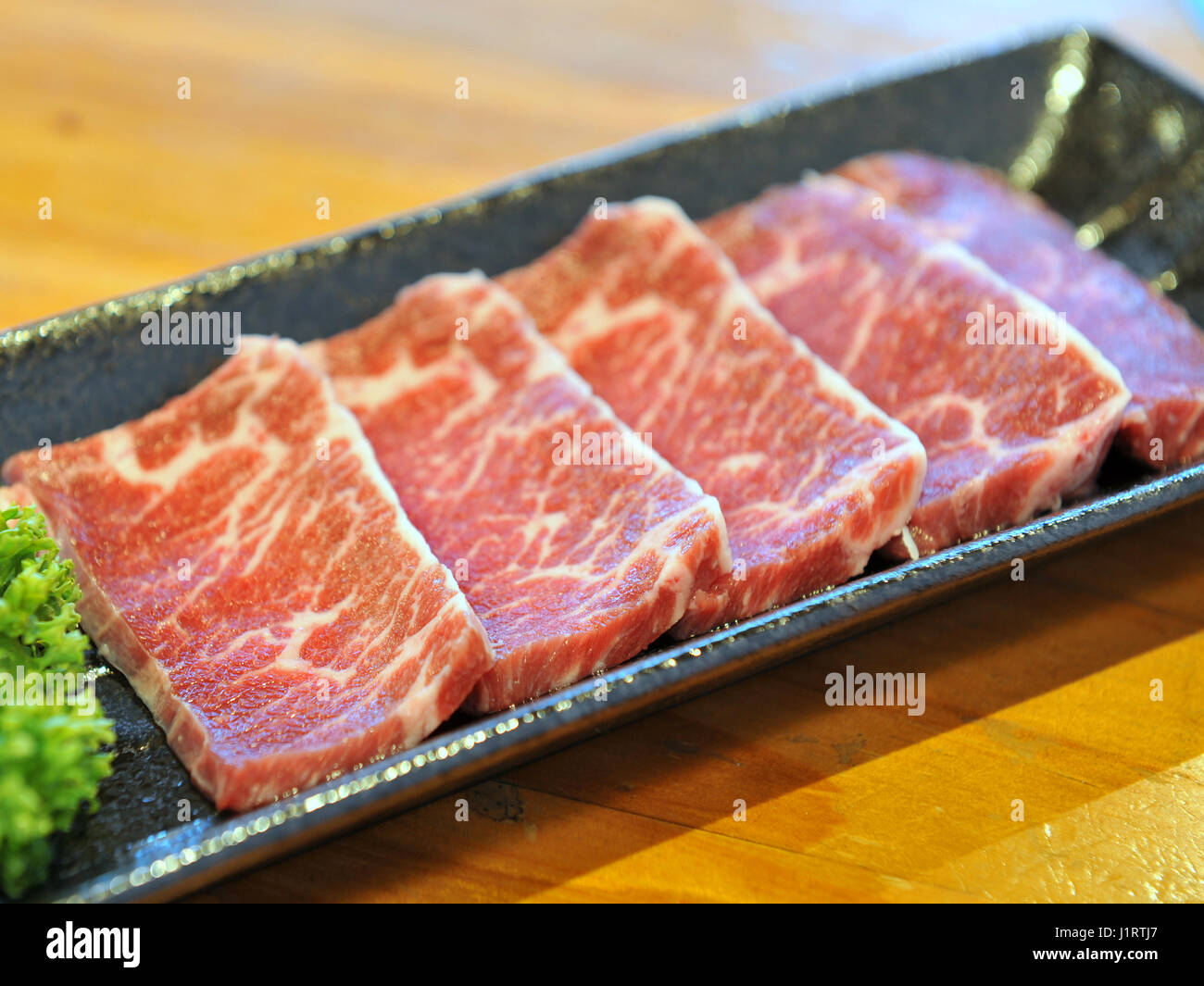 Frische Rohe geschnittene Rindfleisch auf schwarzem Teller Stockfoto
