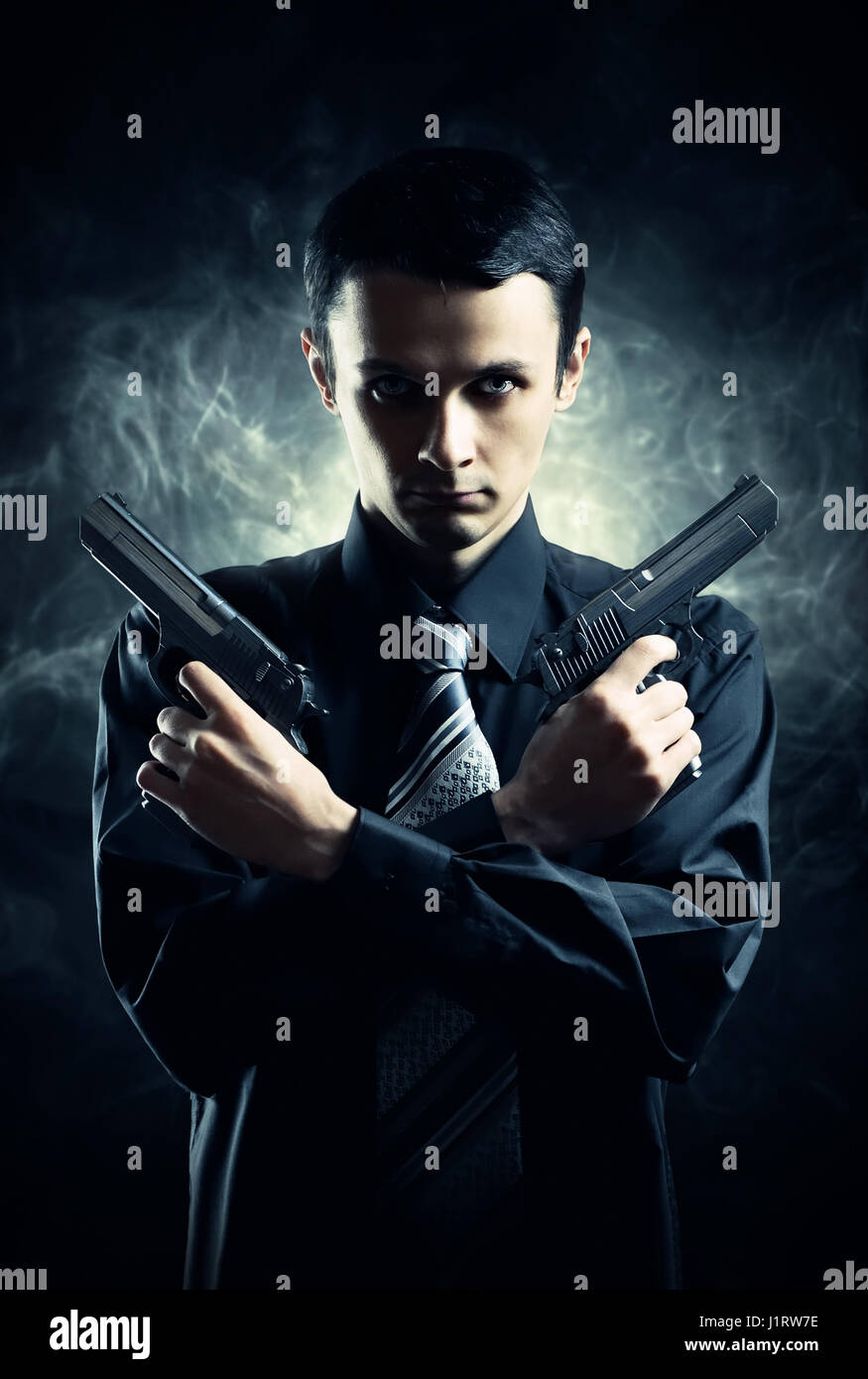 Killer mit zwei Pistolen auf dunklem Hintergrund Stockfoto