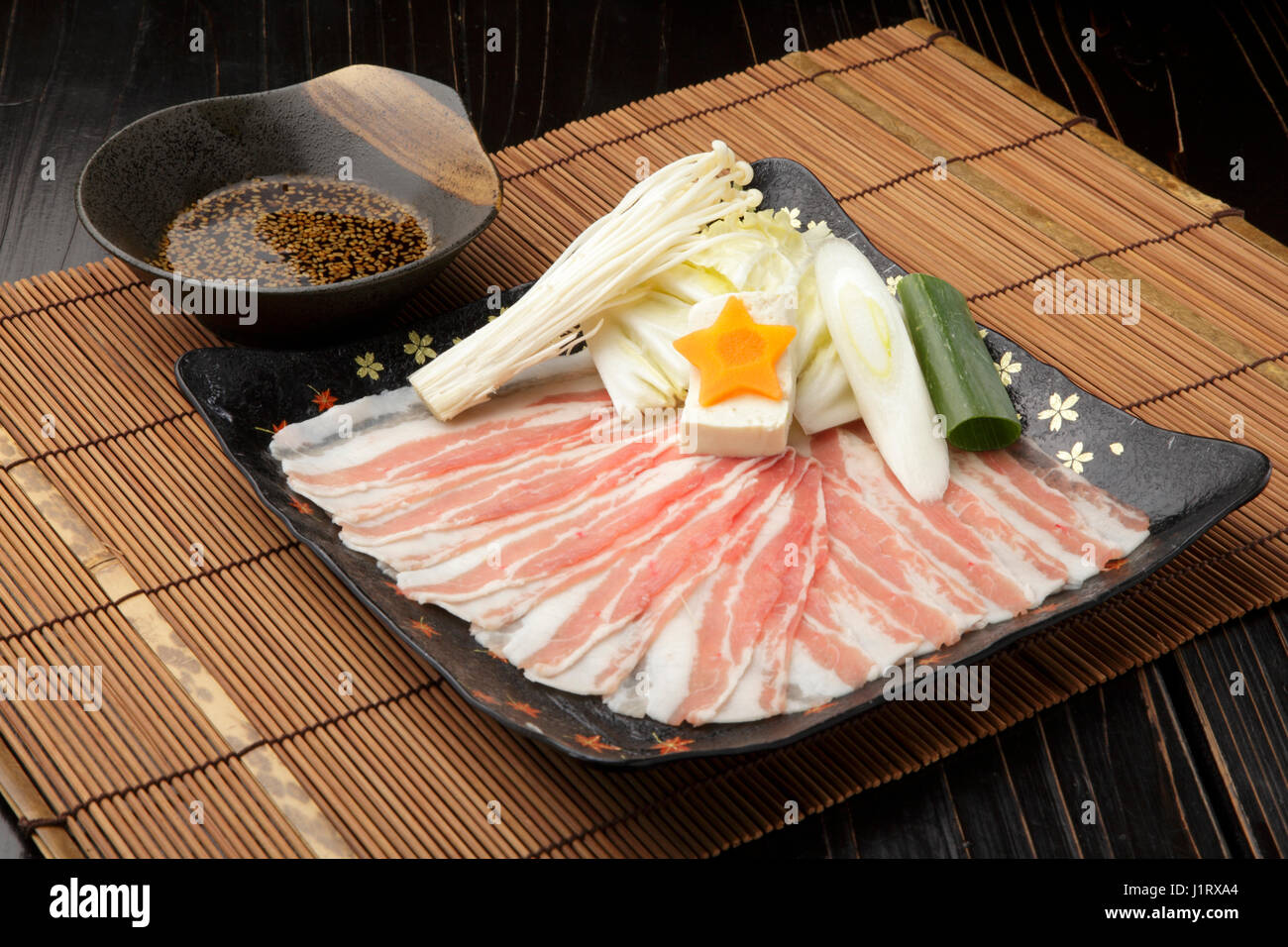 Frisch geschnittenes Schweinefleisch auf schwarzem Teller mit Champignons, Zwiebeln und sauce Stockfoto