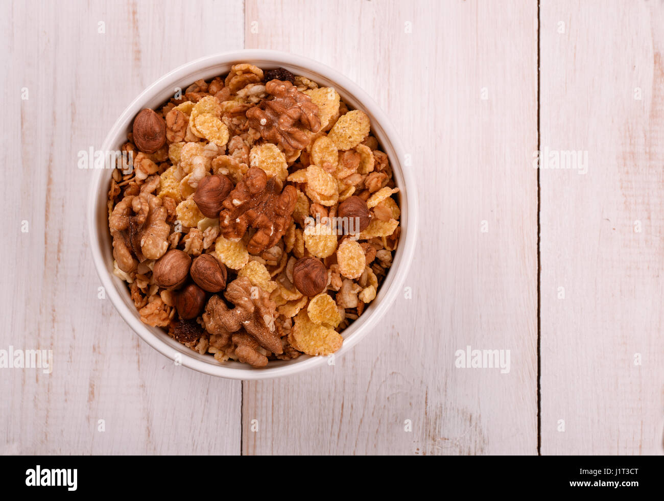 Draufsicht von Cornflakes und Nüssen in Schüssel auf Holztisch Stockfoto