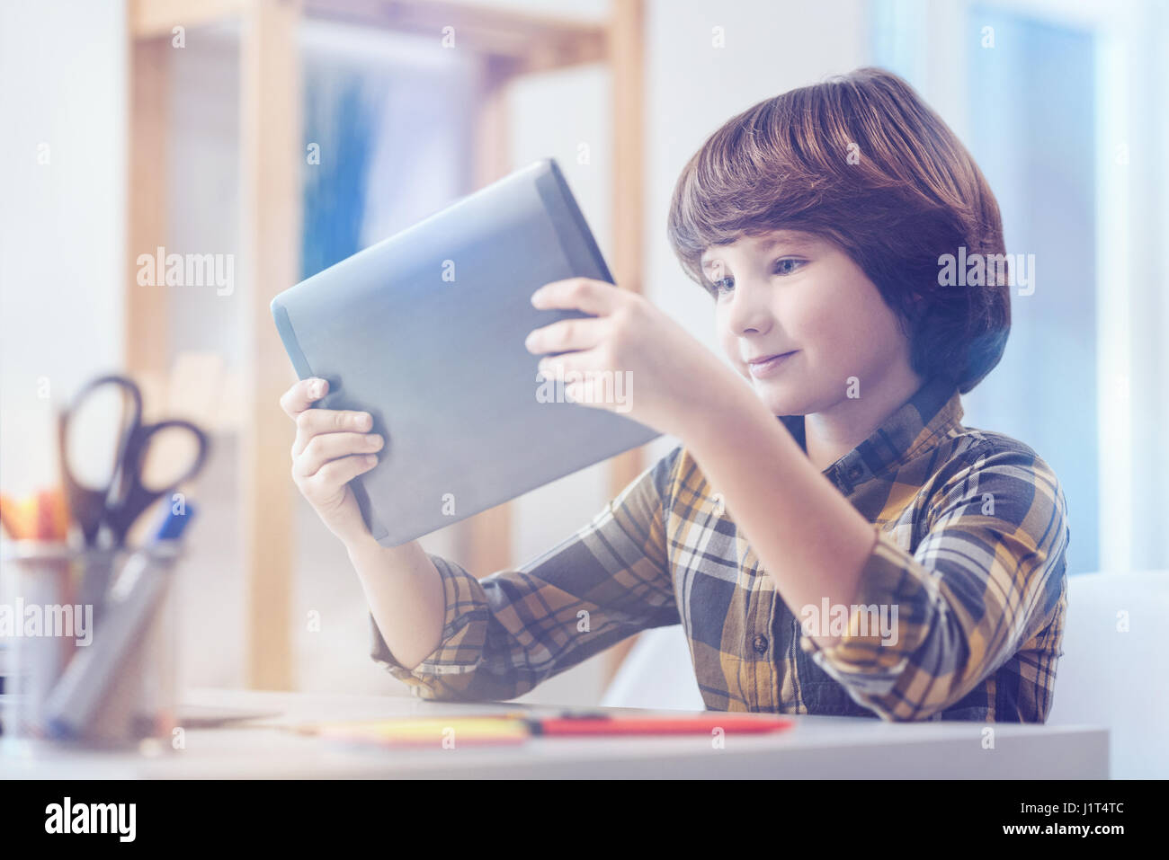 Süsser Boy in kariertes Hemd Blick auf digital-Tablette Stockfoto