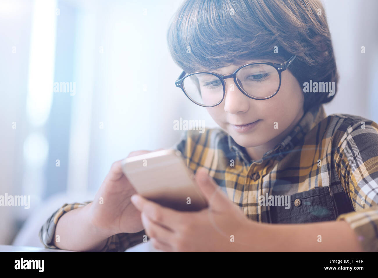Niedlichen kleinen Jungen mit großen Gläsern mit Telefon Stockfoto
