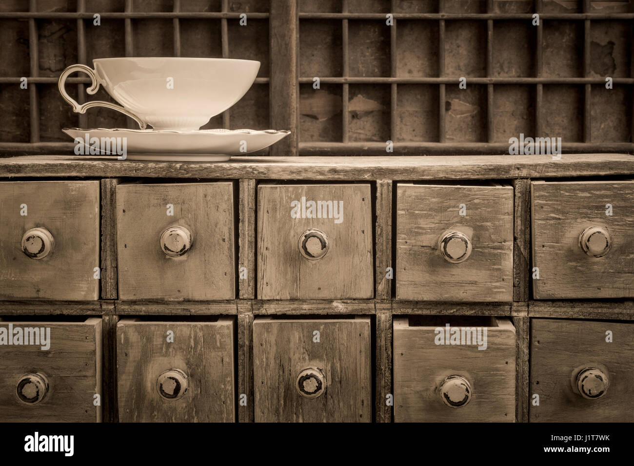 klassische Teetasse auf rustikalen Apotheker Schublade Schrank, schwarz / weiß Platin getönt Stockfoto