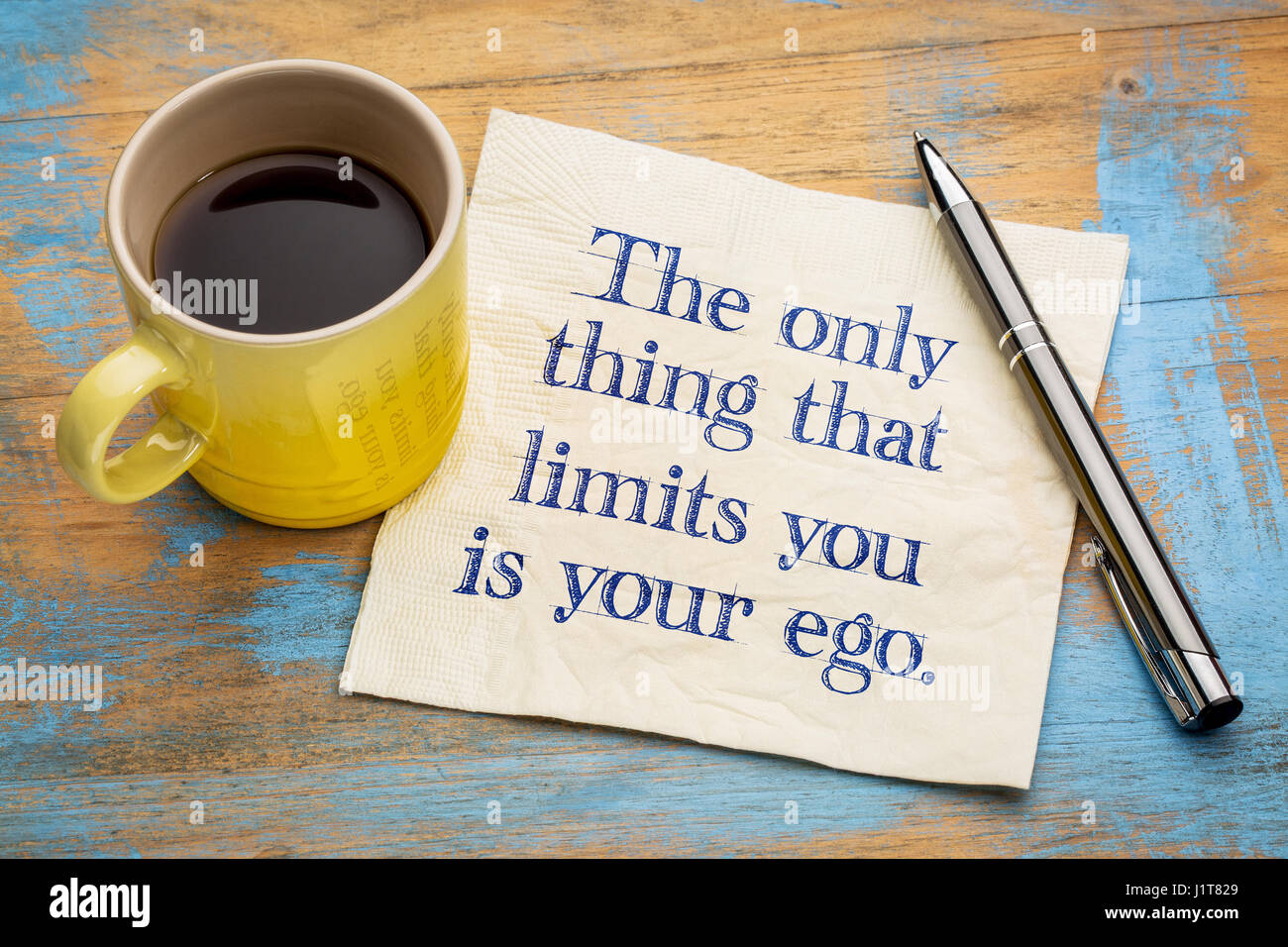 Das einzige, das was Sie Grenzen ist Ihr Ego - Handschrift auf einer Serviette mit einer Tasse Espressokaffee Stockfoto