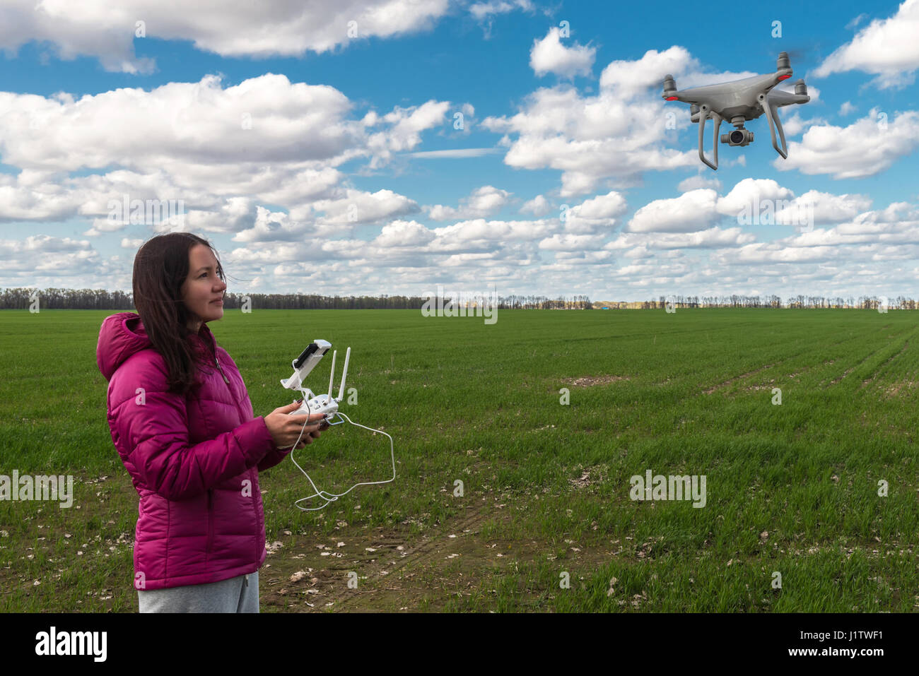 Mädchen von fliegenden Drohne Quadrocopter auf der grünen Wiese in Betrieb. Stockfoto