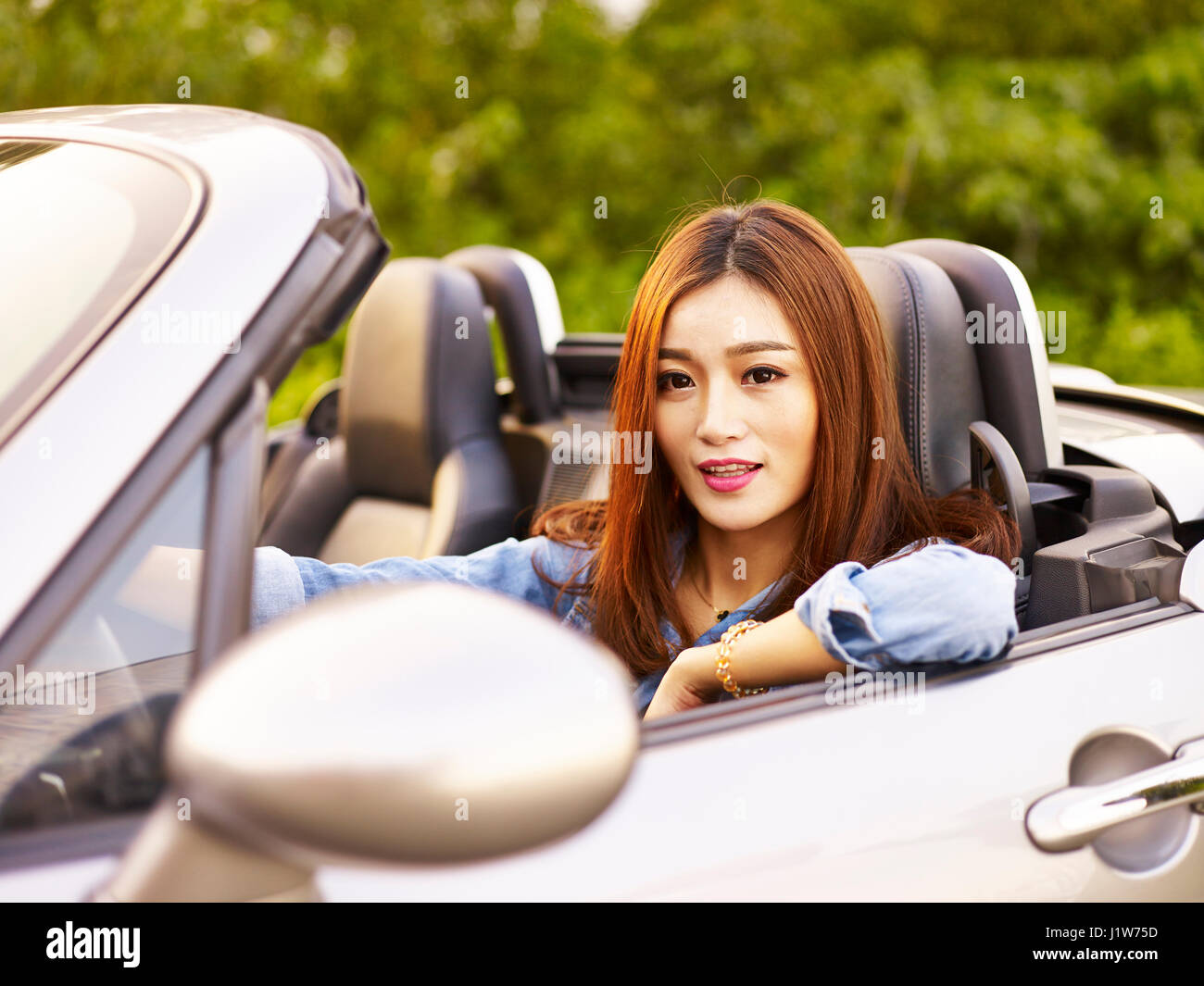 junge asiatische Frau Reiten in einem Cabrio-Sportwagen. Stockfoto