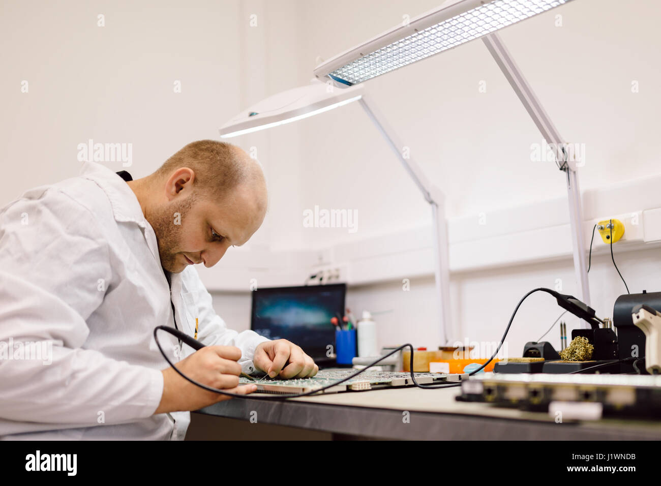 Techniker, die Festsetzung Motherboard durch Löten chips Stockfoto