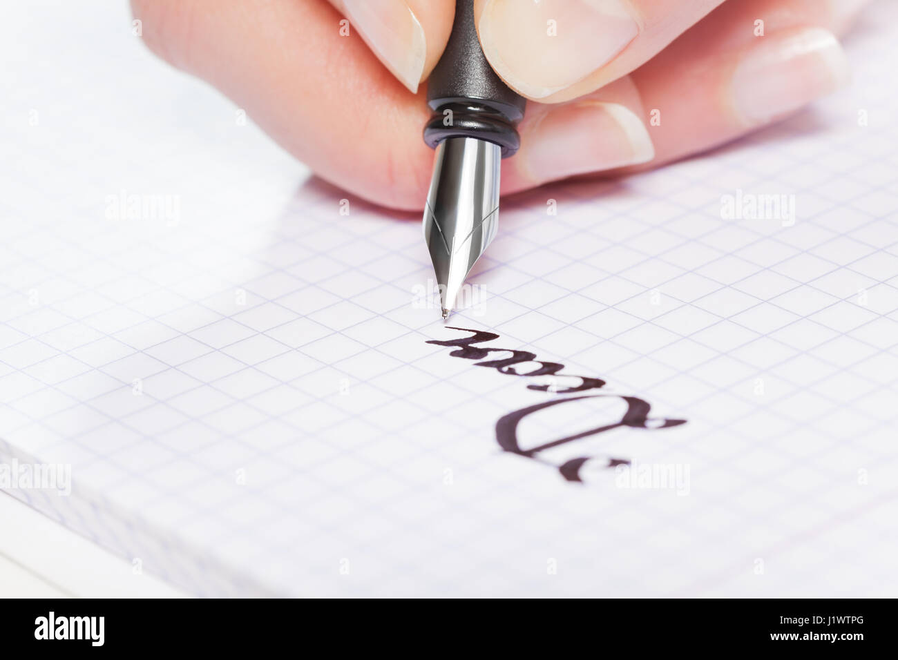 Zarte Frauenhand schreiben das Wort Liebe mit Füllfederhalter auf quadratischen notebook Stockfoto