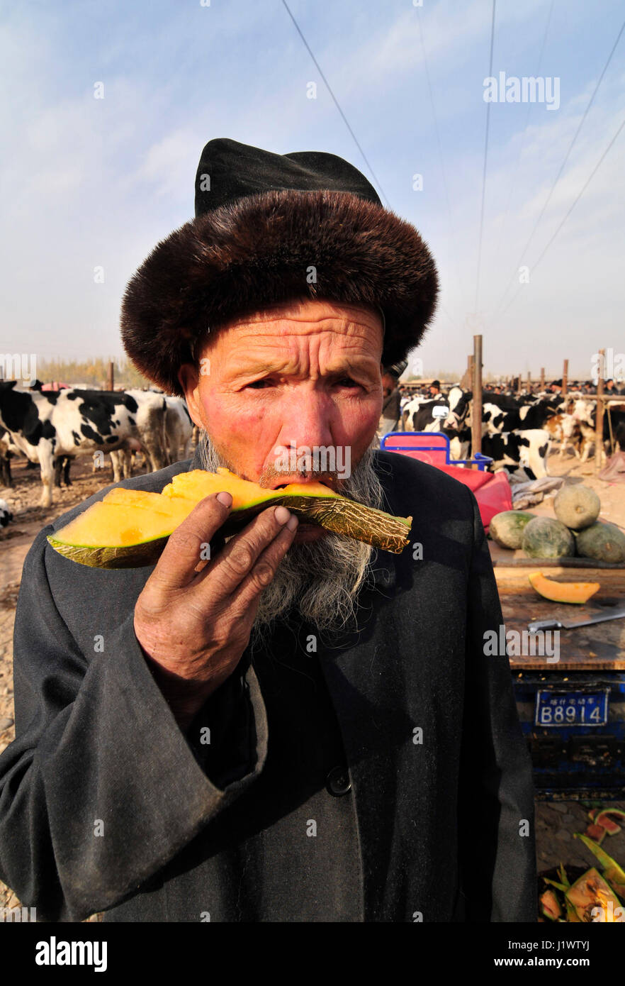 Ein Uyghur Mann genießen eine süße Hami Melone auf dem Markt in Kashgar, Xinjiang, China. Stockfoto