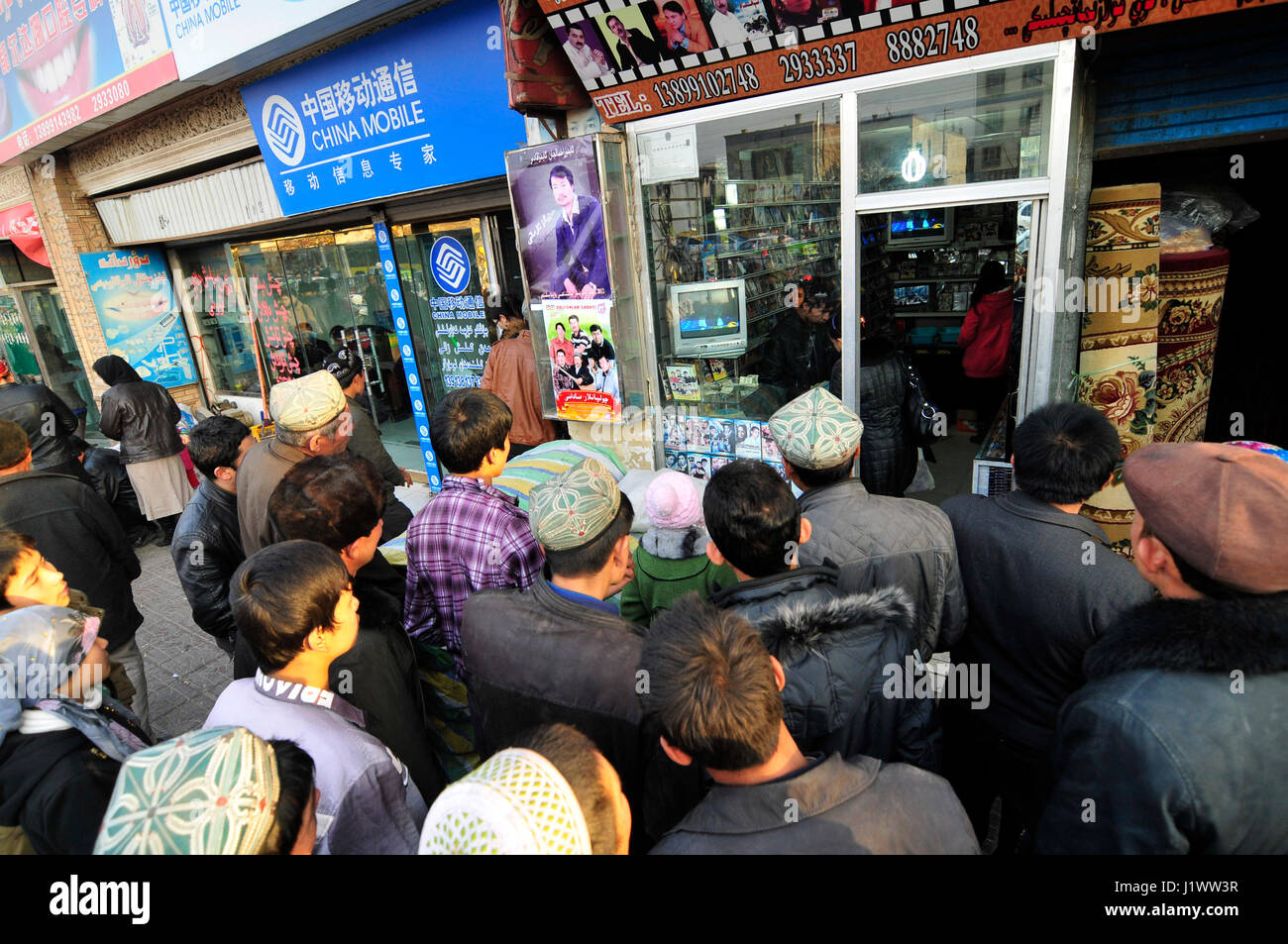 Uigurische Männer Fernsehen während auf einer Straße in Kashgar, China stehen. Stockfoto
