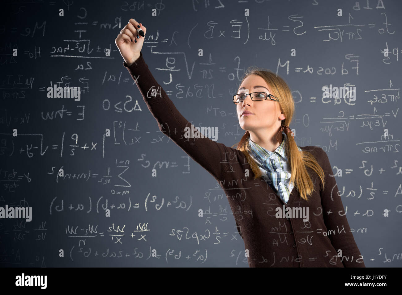 Schulmädchen-Arbeitseinsätze in Mathematik auf transparente Wand Stockfoto