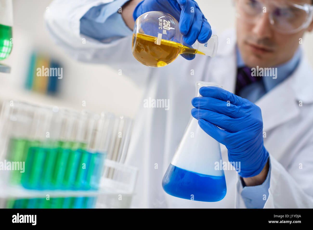 Männliche Forscher untersuchen Flaschen mit verschiedenen Proben im Labor Stockfoto