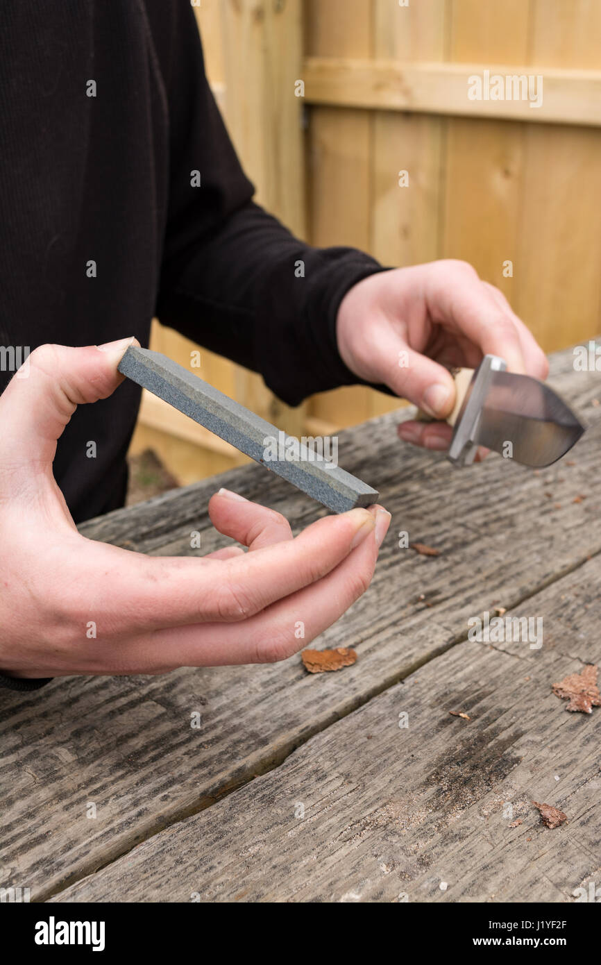 Männliche Hände mit einem Schleifstein schärfen große Taschenmesser. Stockfoto