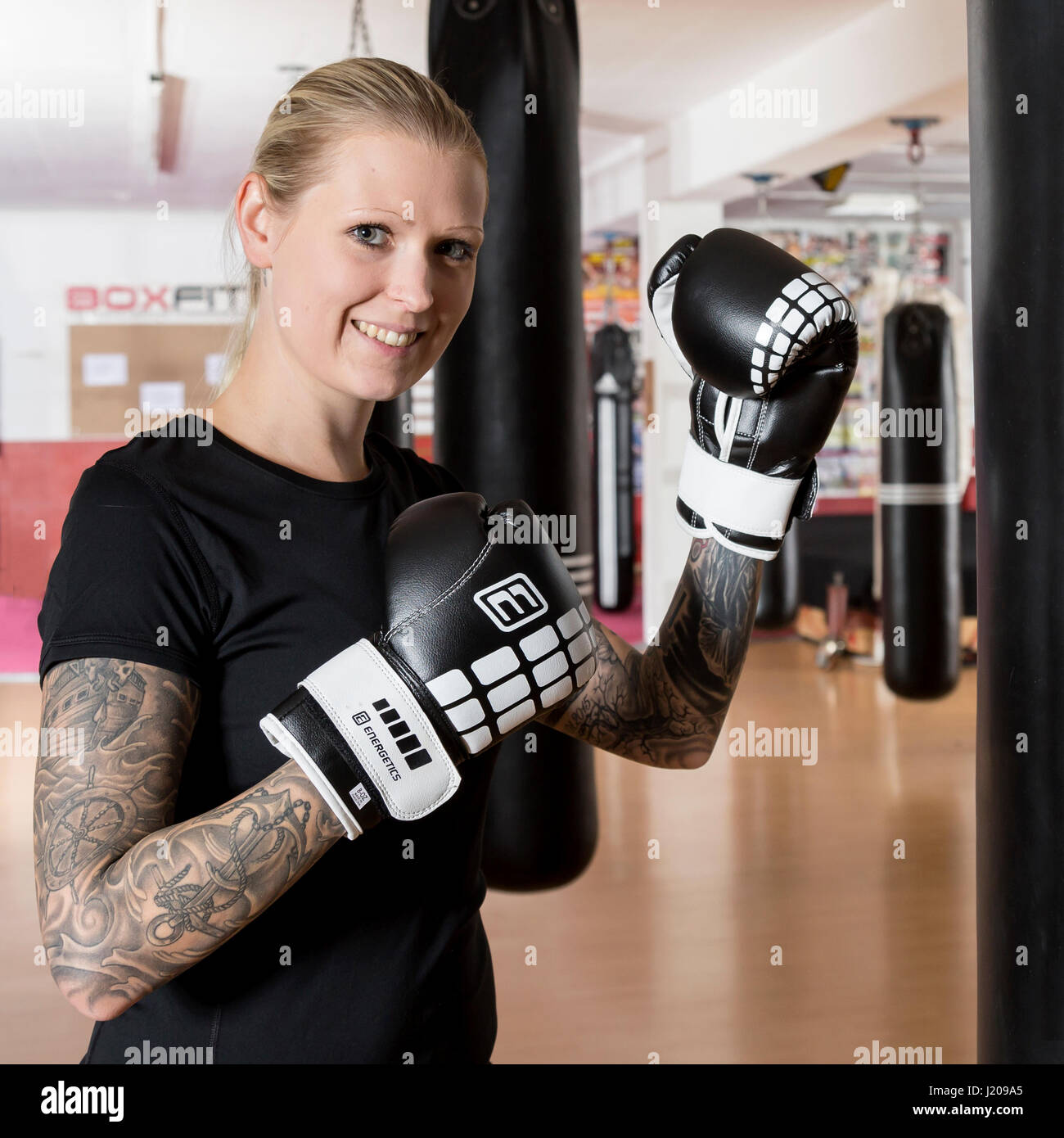 Junge Frau, tätowiert, Boxen an einem Sandsack in einem Box-Studio, Bayern, Deutschland Stockfoto