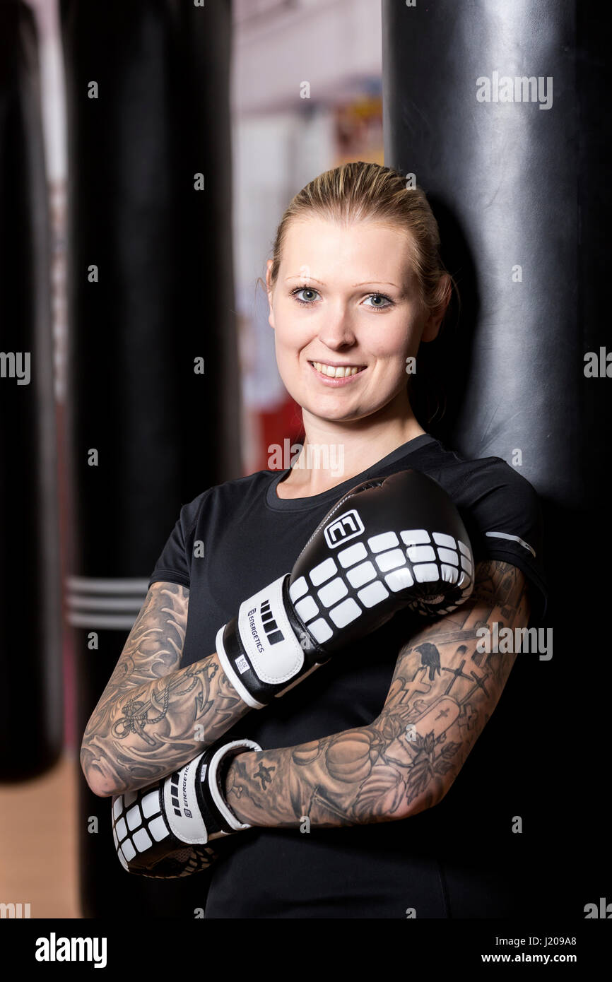 Junge Frau, tätowiert, Boxen an einem Sandsack in einem Box-Studio, Bayern, Deutschland Stockfoto