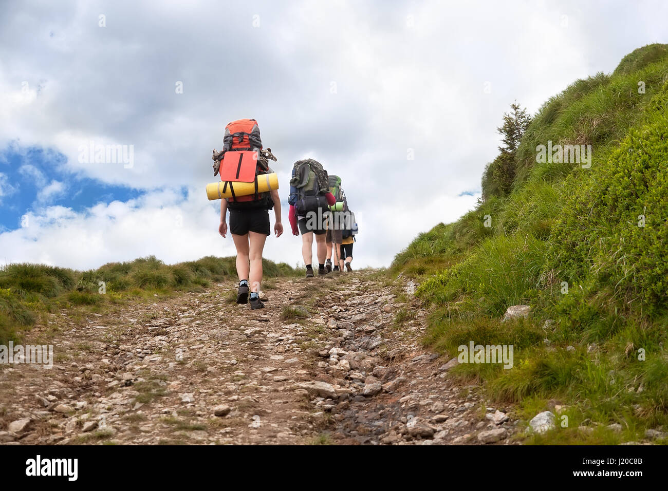 Gruppe von Wanderern mit Rucksäcken unterwegs in den Bergen. Aktivurlaub. Touristen auf Schotterstraße wandern. Gesunde Lebensweise, Abenteuer, active Leisure Stockfoto