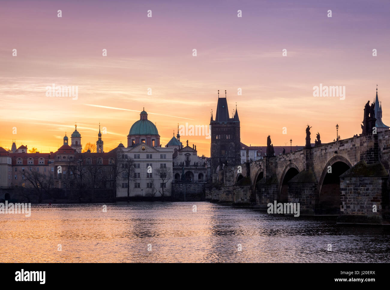 Prag, Tschechische Republik. Karlsbrücke mit der Statue und Sonnenaufgang über der Brücke, Altstädter Brückenturm im Hintergrund. Stockfoto
