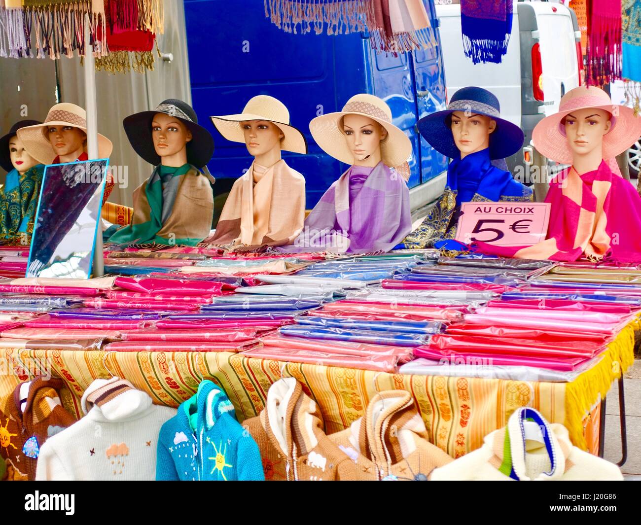 Sieben Mannnequins tragen hell gefärbt Sonnenhüte, plus, gefaltet lebhaft gefärbten Schals verkauft an einem Stand, Sonntagsmarkt Bastille, Paris, Frankreich. Stockfoto