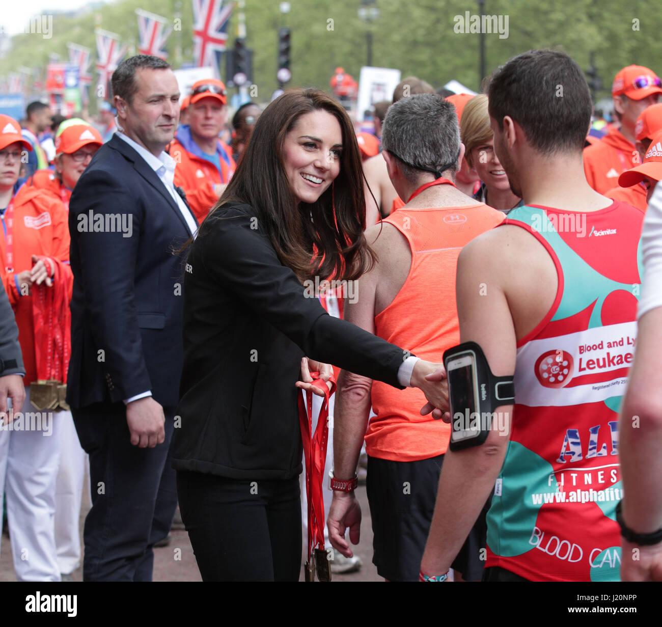 Die Herzogin von Cambridge präsentiert einen Läufer mit einer Medaille nach der Überquerung der Ziellinie in der Mall während der Virgin-Geld-London-Marathon. Stockfoto