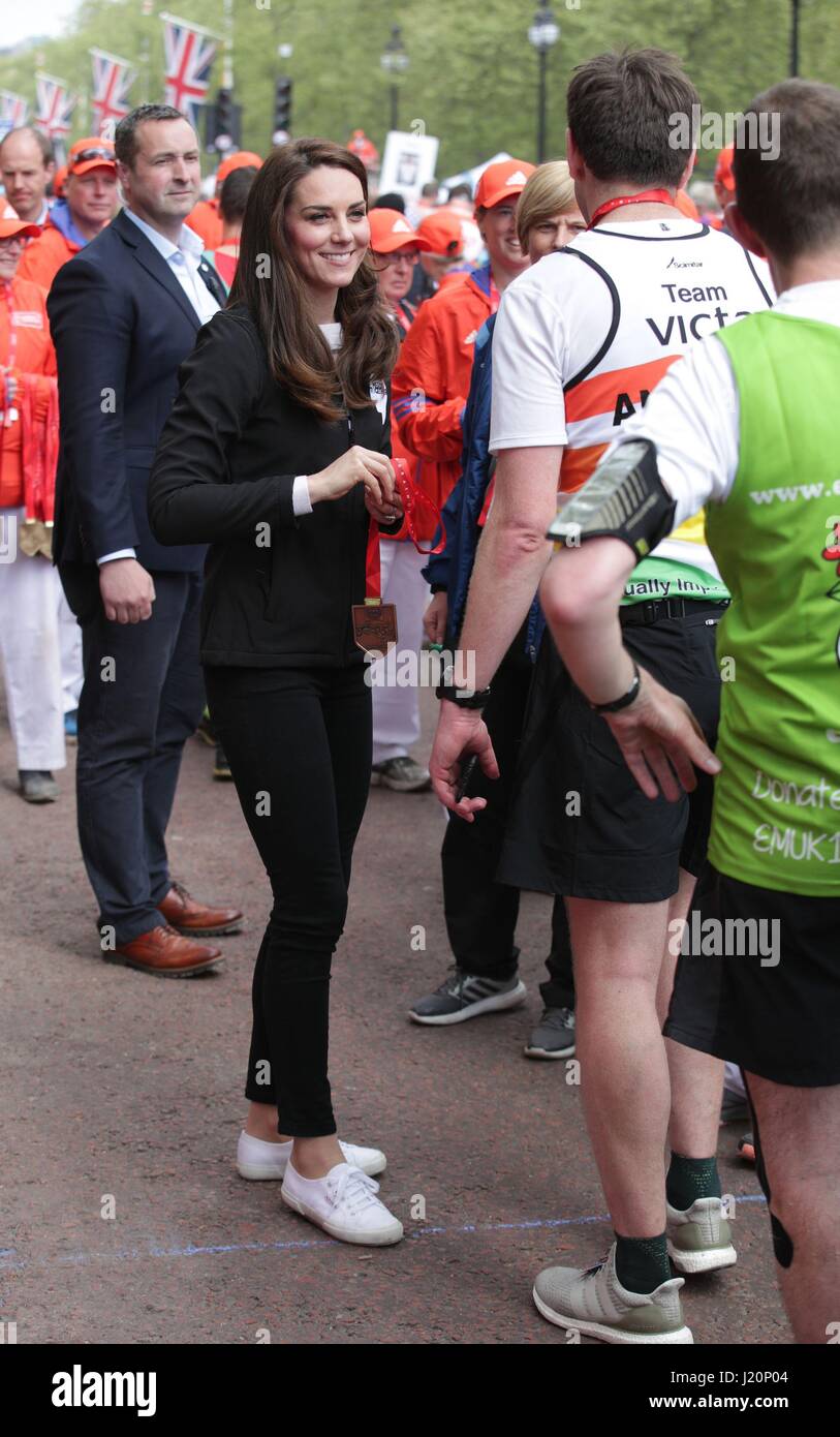 Die Herzogin von Cambridge präsentiert einen Läufer mit einer Medaille nach der Überquerung der Ziellinie in der Mall während der Virgin-Geld-London-Marathon. Stockfoto