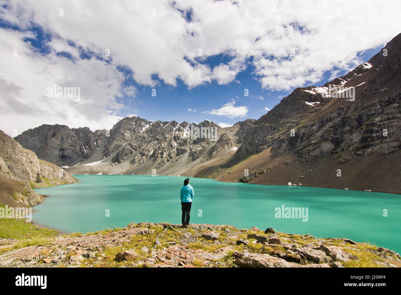 Mädchen im blauen Jacke stehen über blaue ruhigen Berg See Alakol mit Bergen umgeben Stockfoto