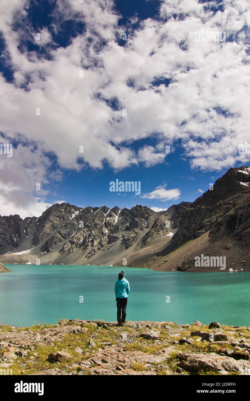 Mädchen im blauen Jacke stehen über blaue ruhigen Berg See Alakol mit Bergen umgeben Stockfoto
