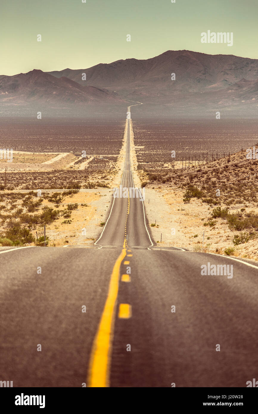 Klassische vertikale Ansicht einer endlosen geraden Straße laufen durch die karge Landschaft des amerikanischen Südwestens mit extremer Hitze Dunst im Sommer Stockfoto Klassische vertikale Ansicht einer endlosen geraden Straße laufen durch die karge Landschaft des amerikanischen Südwestens mit extremer Hitze Dunst im Sommer Stockfoto