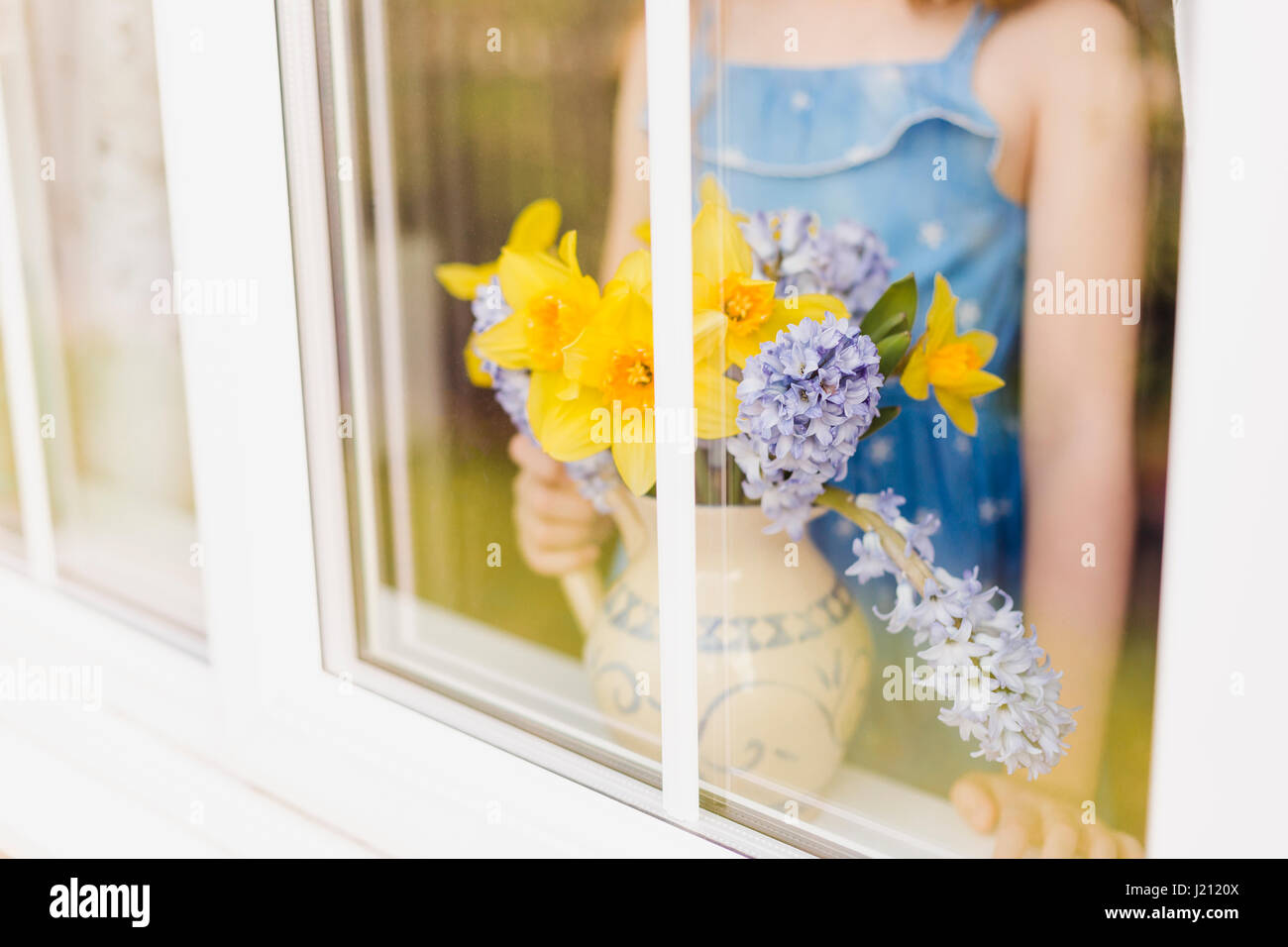 Blumen-Vase von Narzissen und Hyazinthen hinter Fensterscheibe Stockfoto