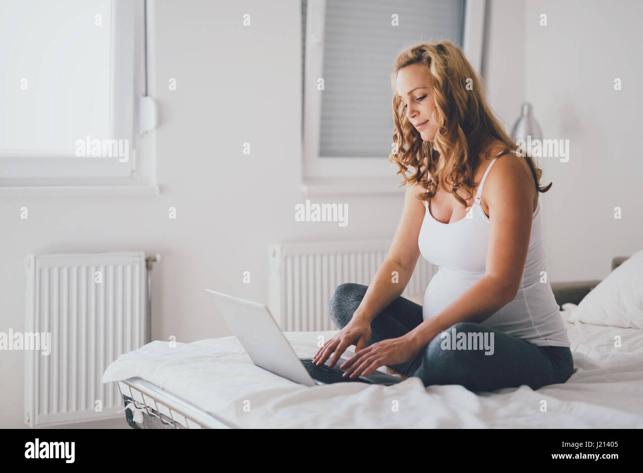 Werdende und glücklich Schwangere mit Technologie von zu Hause aus Stockfoto