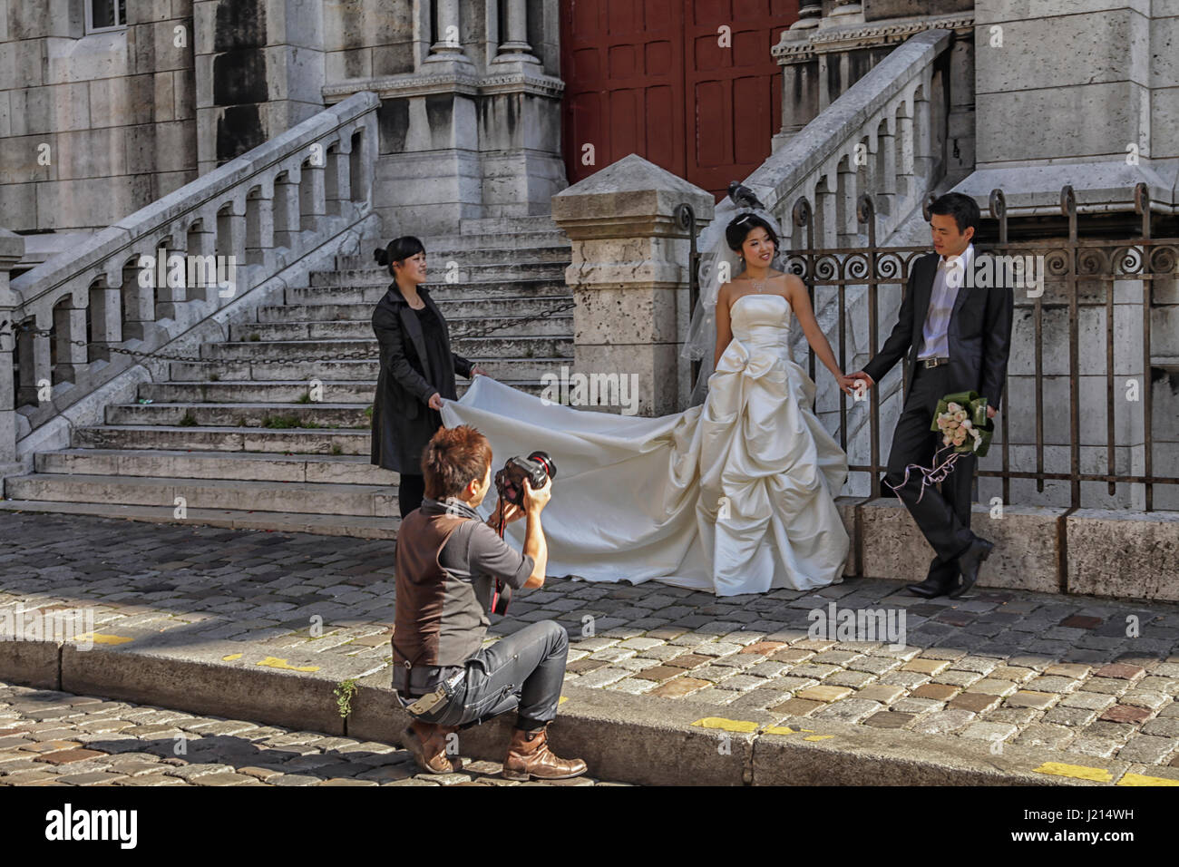 Strahlende asiatische Braut & Bräutigam posieren für Fotografen unter Hochzeit Porträt in Paris Stockfoto