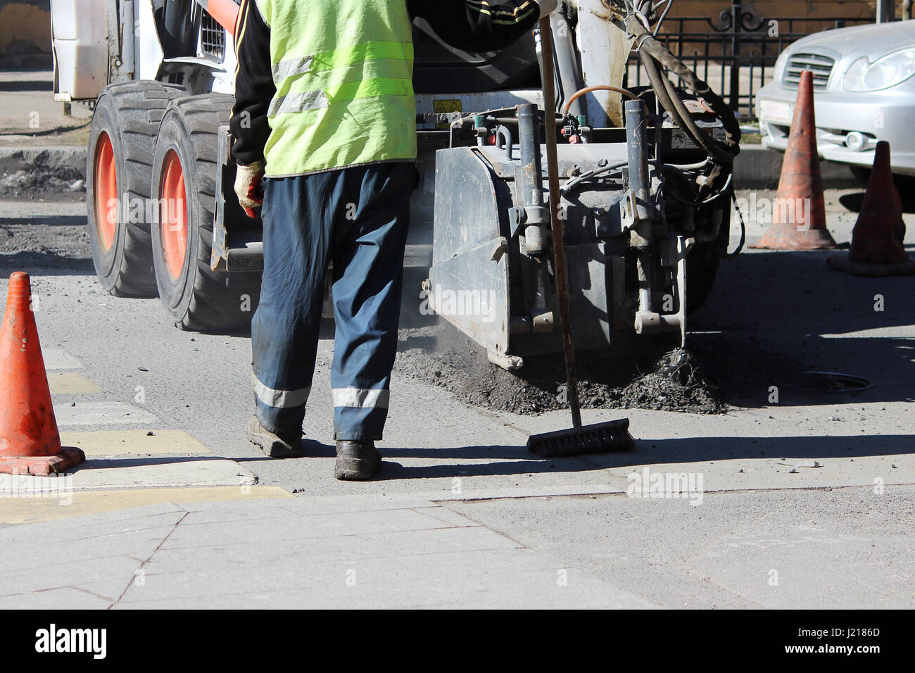 Demontage der Asphaltdecke auf der Straße während der Fahrt Maschinen mit Hilfe von einem Mini-Hydro-Hammer während der Reparatur Straße Stockfoto