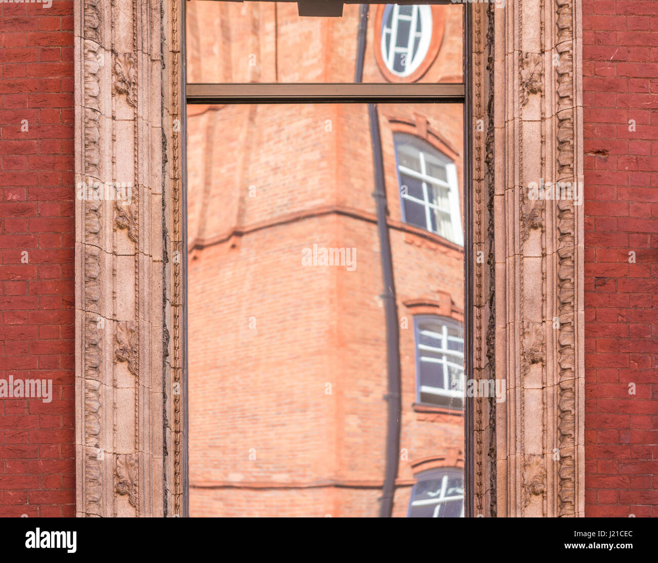 Reflektion von einem alten Backsteingebäude in London in einem Fenster mit kunstvollen Formen, London, England, Grossbritannien Stockfoto