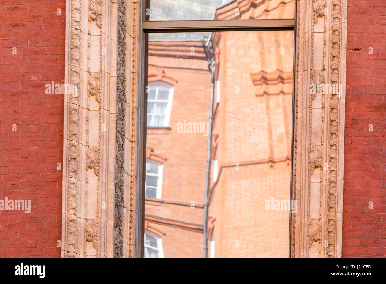 Reflektion von einem alten Backsteingebäude in London in einem Fenster mit kunstvollen Formen, London, England, Grossbritannien Stockfoto