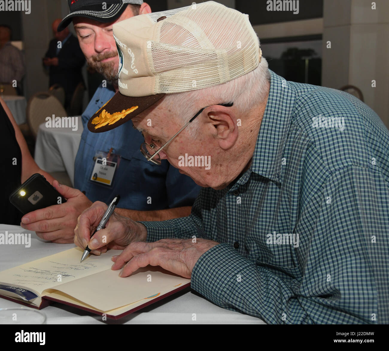 Eine 307th Bombe Flügel Alumni signiert ein Buch über die Geschichte der 307th Bombardment Group bei einem Wiedersehen Eisbrecher Event im Shreveport Convention Center, Shreveport, Louisiana, 30. März 2017. 307th BW veranstaltet ein Treffen anlässlich des 75. Jubiläums des Geräts und inklusive Alumni aus Kriegen wie dem zweiten Weltkrieg, Koreakrieg, Vietnam und des Kalten Krieges. (US Air Force Foto von Staff Sgt. Callie Ware/freigegeben) Stockfoto