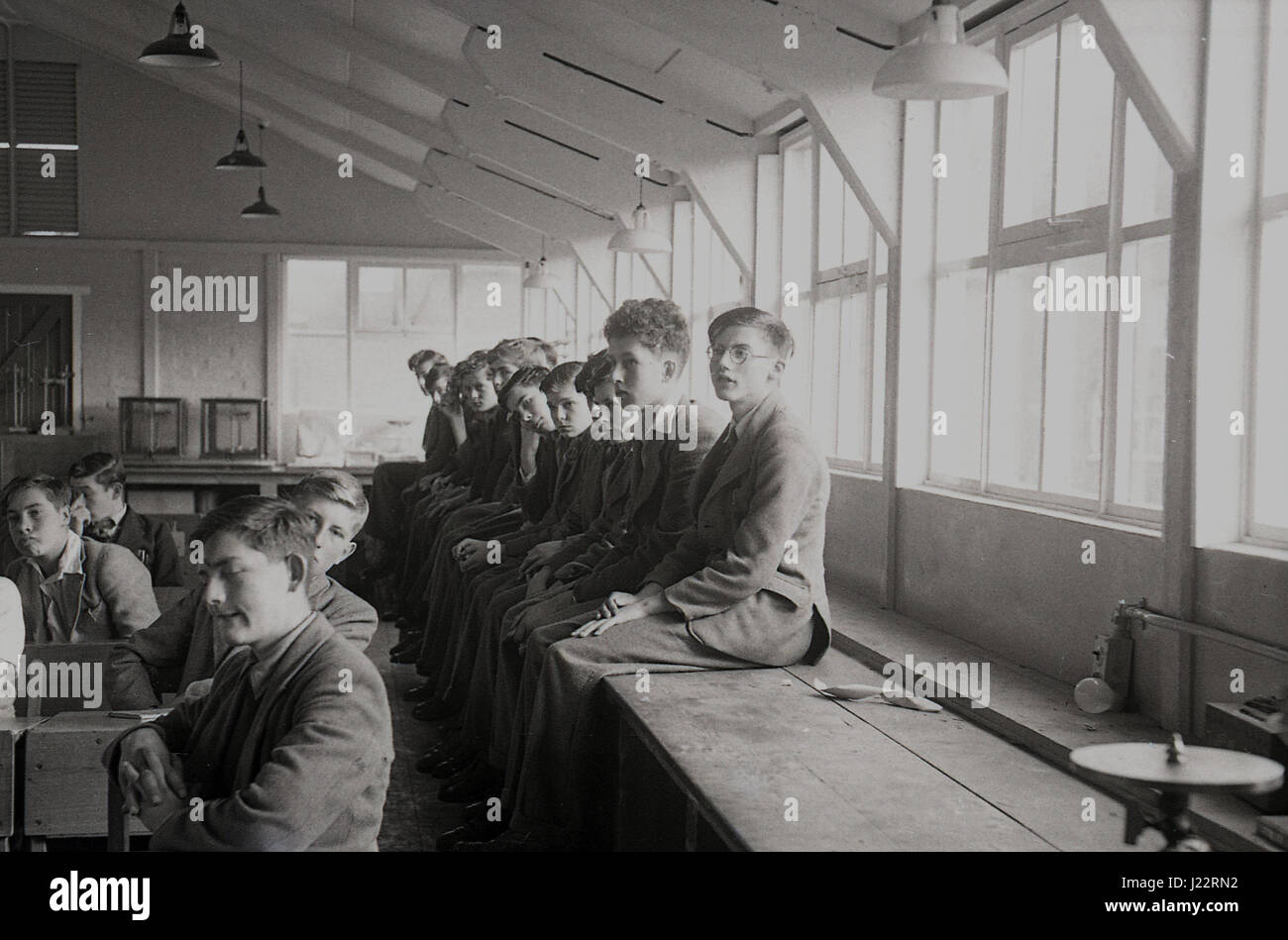 1950, sprechen junge Männer sitzen am Schreibtisch und auf Werkbänken in Klassenzimmer anhören Offizier Arm die Gesundheitsbehörden Zwangsverpflichtung oder nationalen Serivce, England, UK. Stockfoto