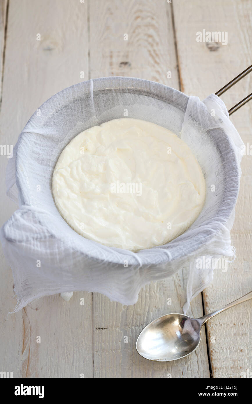 Belastungsprobe für Joghurt durch Musselin über ein Sieb, griechischen Stil Joghurt machen. Stockfoto