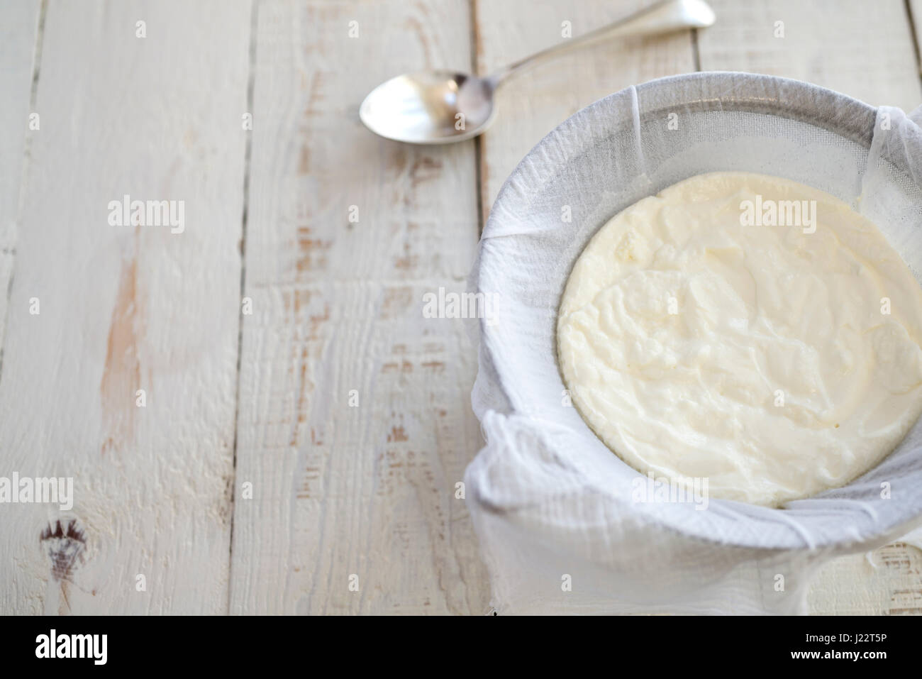 Belastungsprobe für Joghurt durch Musselin über ein Sieb, griechischen Stil Joghurt machen. Stockfoto