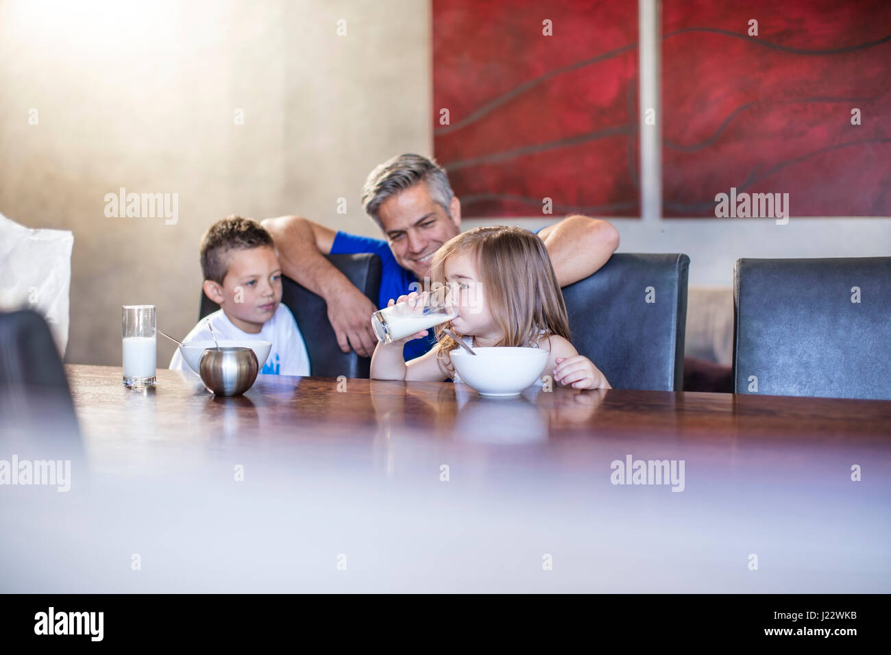 Glücklicher Vater mit Kindern sitzen beim Frühstück am Tisch Stockfoto