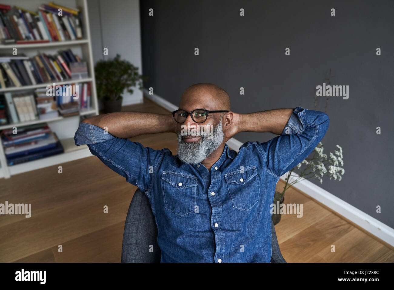 Reifer Mann sitzt entspannt zu Hause Stockfoto