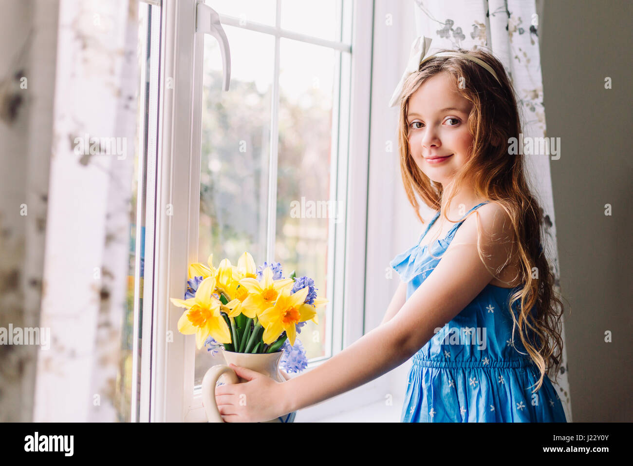 Porträt von lächelndes Mädchen mit Blumen-Vase von Narzissen und Hyazinthen zu Hause Stockfoto