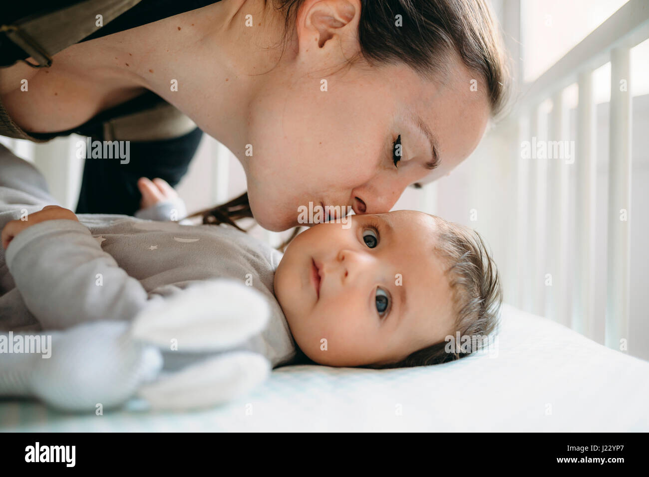 Mutter, küssen ihr Baby in der Krippe Stockfoto