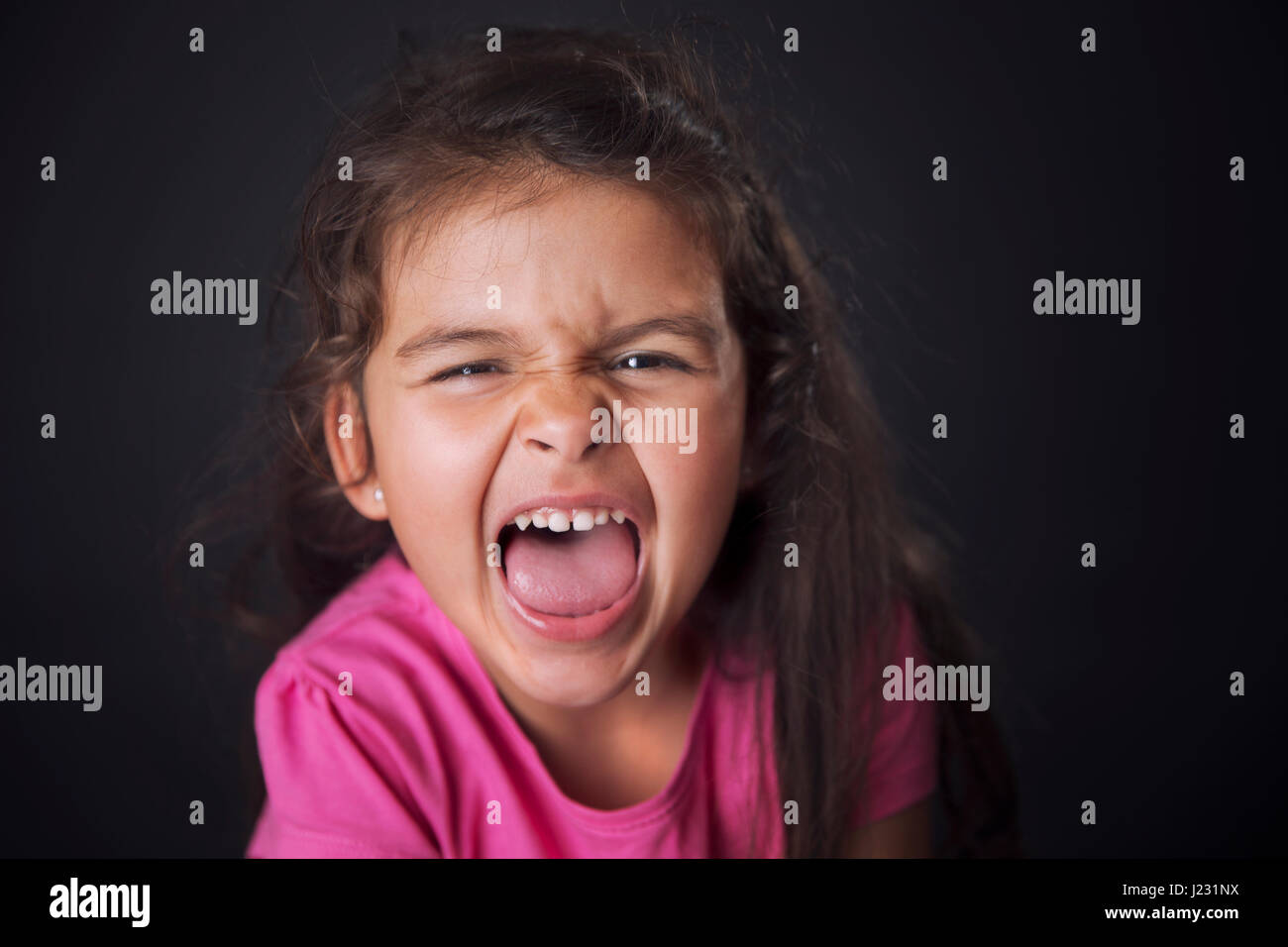 Kleines Mädchen im rosa Hemd schreien ausdrücklich beim Blick in die Kamera. Stockfoto