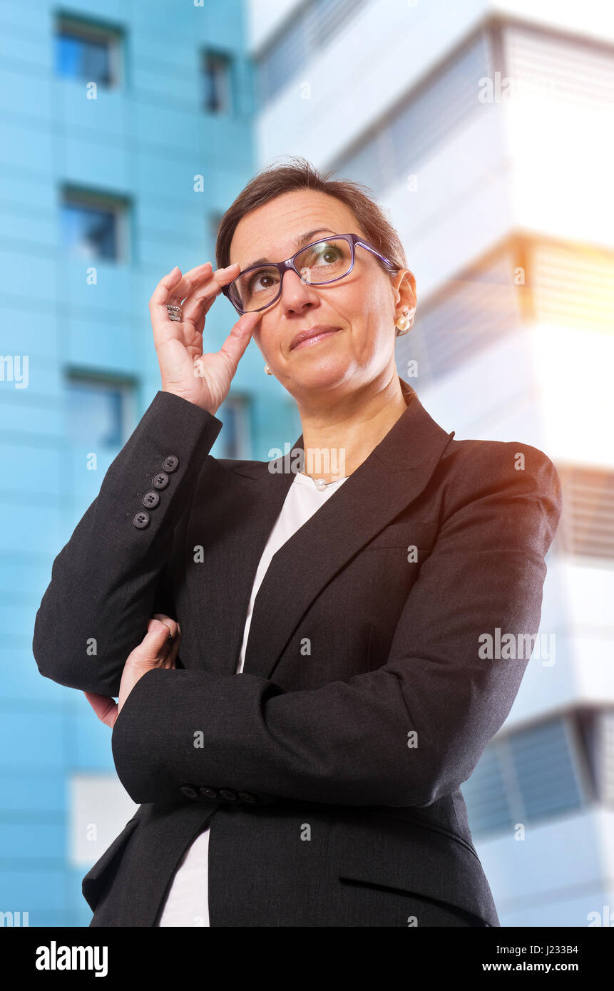 Brünette Business-Frau mit Brille posiert vor Bürogebäude Stockfoto