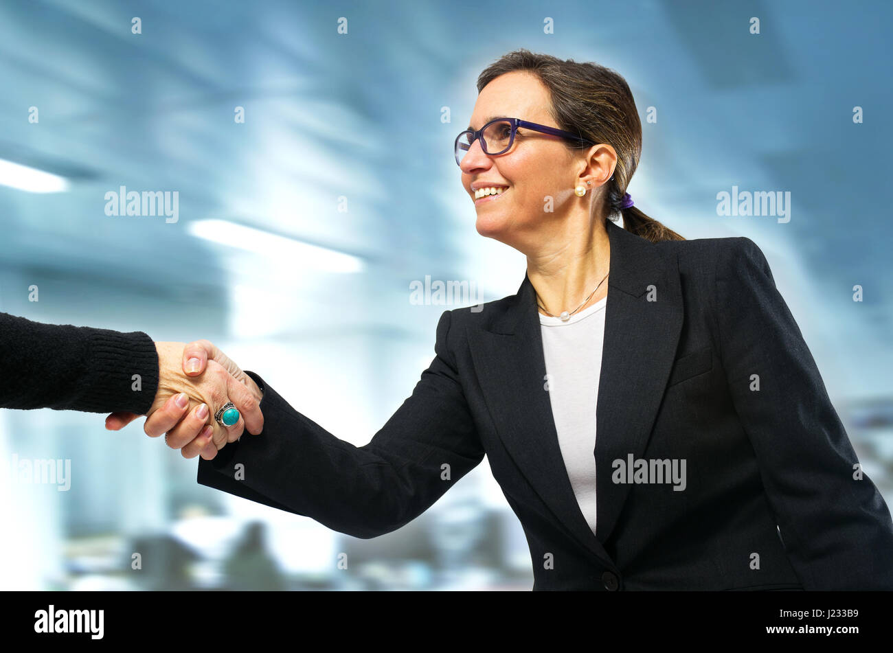 Business-Frau, die einen Besuch in ihrem Büro mit einem Handschlag Gruß Stockfoto