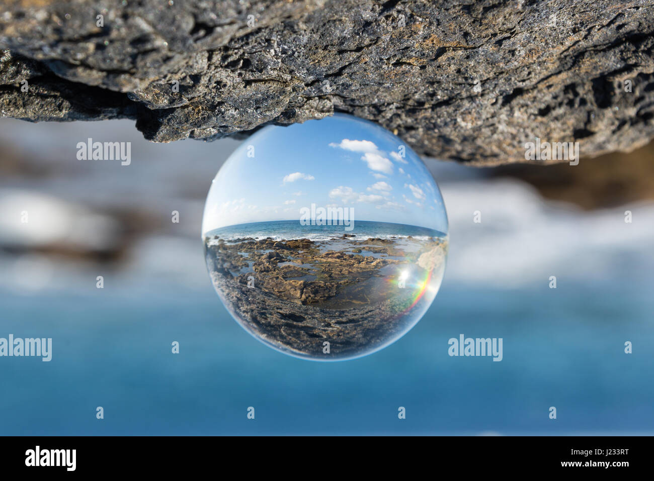 Landschaft mit Meer und Felsen durch eine Glaskugel zu sehen Stockfoto