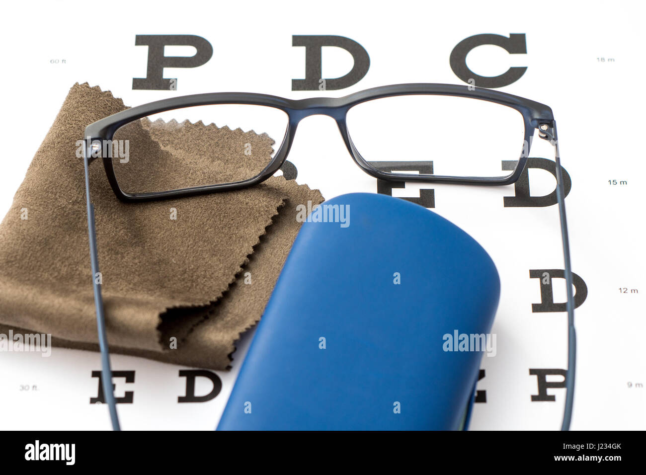 Schwarze Brillen, braun Mikrofaser Tuch und blau Schutzhülle mit weißem Auge Diagramm Nahaufnahme Reinigung lesen Stockfoto