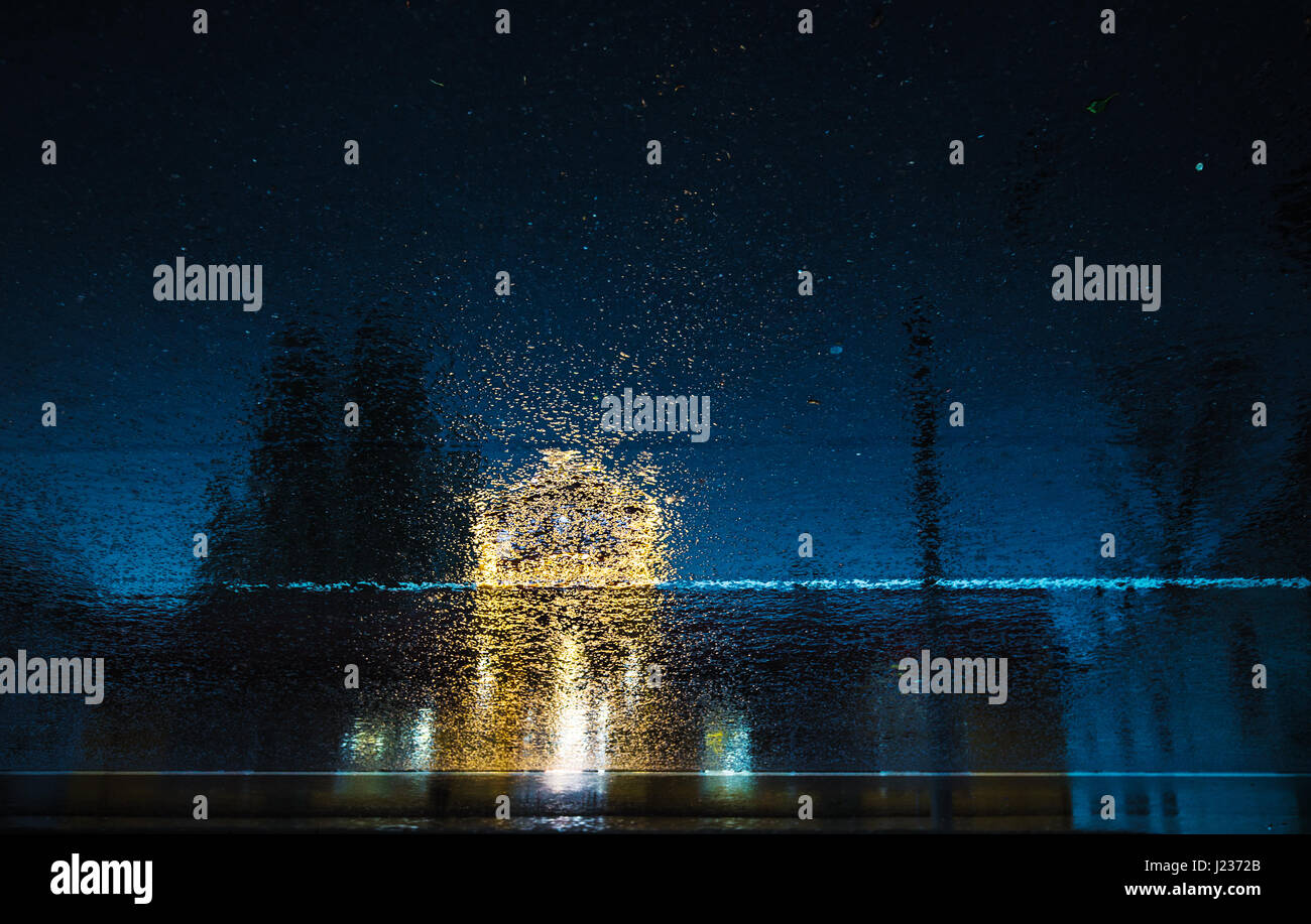 Foto des Lichts von den Gebäuden reflektiert auf der nassen Straße. Stockfoto