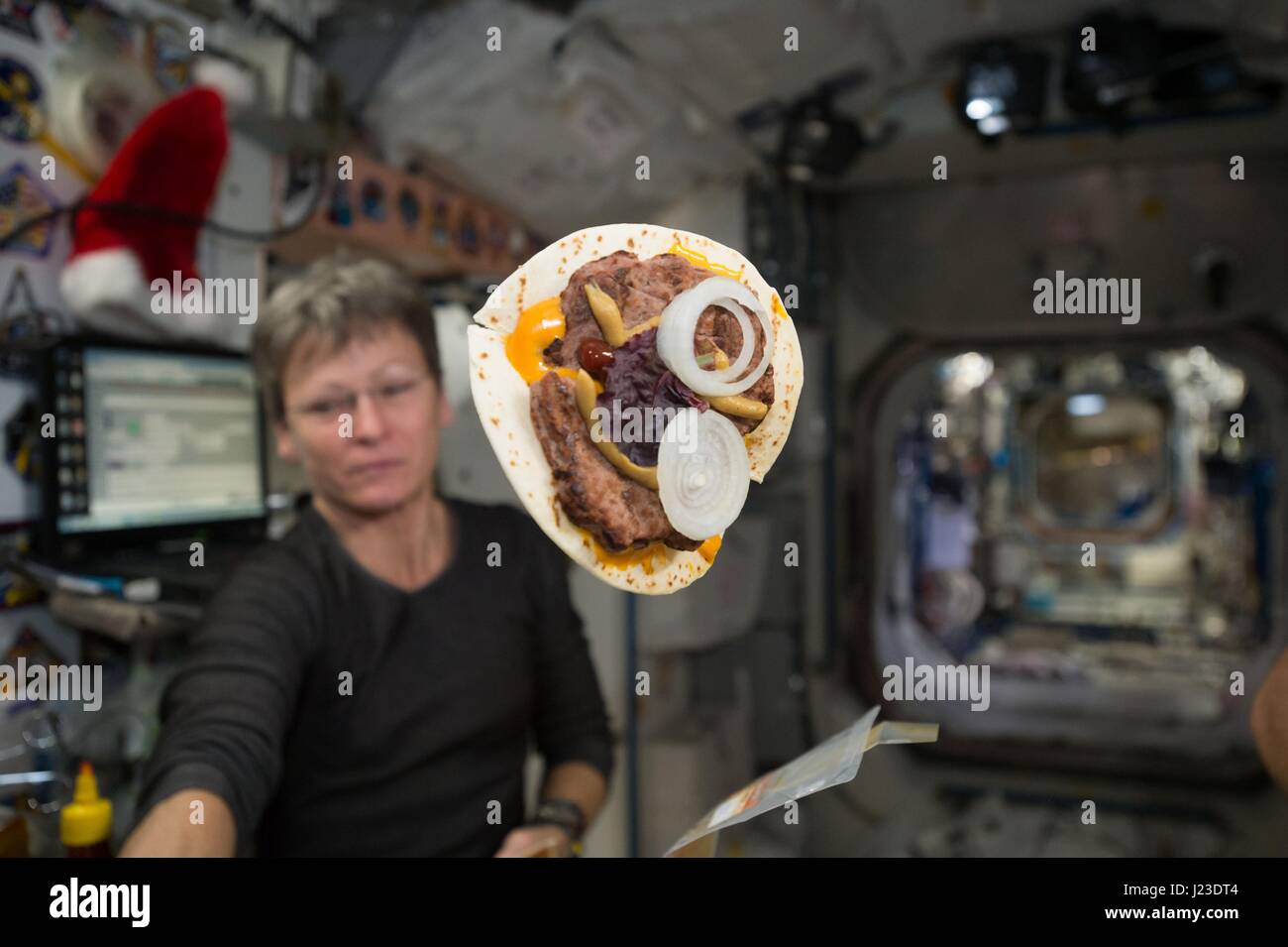 NASA-Expedition 50 erstklassige Besatzung Astronaut Peggy Whitson in der internationalen Raumstation ISS arbeitet, während ein Cheeseburger in einer Tortilla eingewickelt schwebt vor ihrem 24. Dezember 2016 in der Erdumlaufbahn.    (Foto von der NASA über Planetpix) Stockfoto